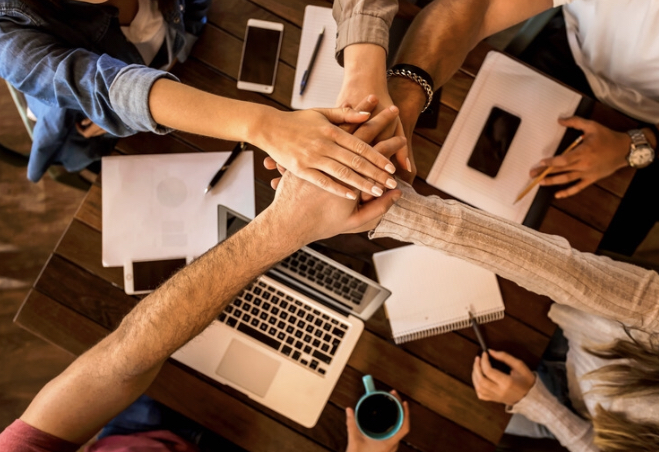 Des mains liées illustrant la solidarité entre entrepreneurs dans le Happy Club de COM’HAPPY